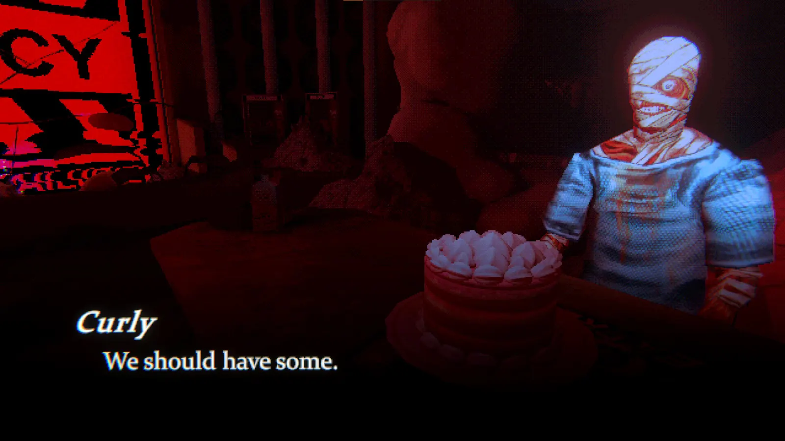 A birthday cake in front of a screen showing bandaged Curly
